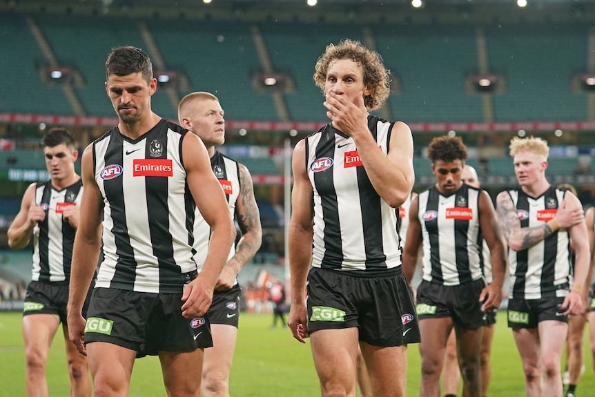 A group of Collingwood AFL players walk off the MCG after a loss to Greater Western Sydney.