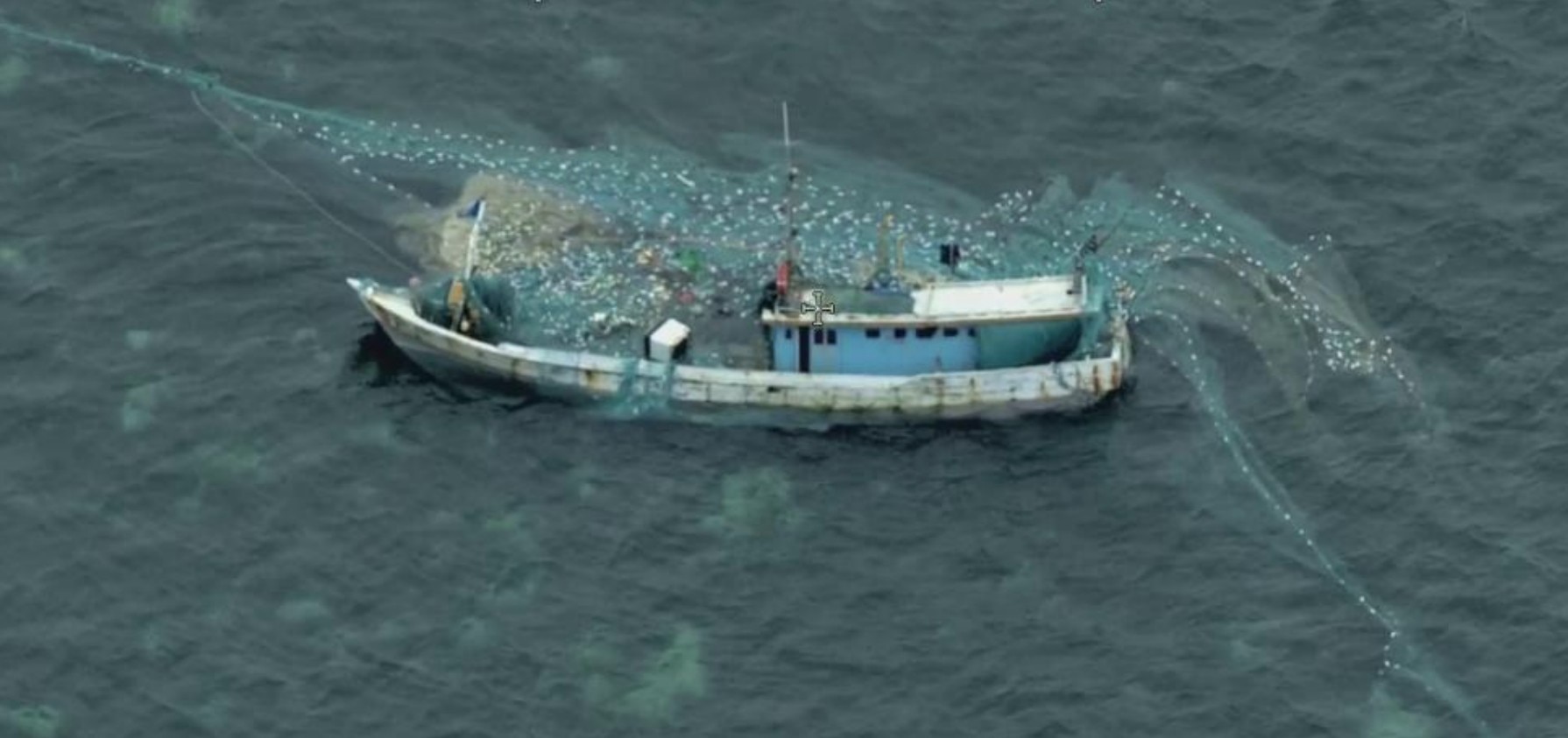 Una vista aérea de las redes de pesca que sobresalen de un pequeño barco pesquero en el agua