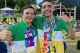 Two gymnasts wearing Team Australia tops smile at the camera wearing their medals from the Special Olympics.