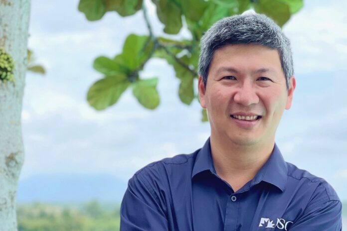 Hombre sonriendo con fondo de naturaleza en segundo plano.