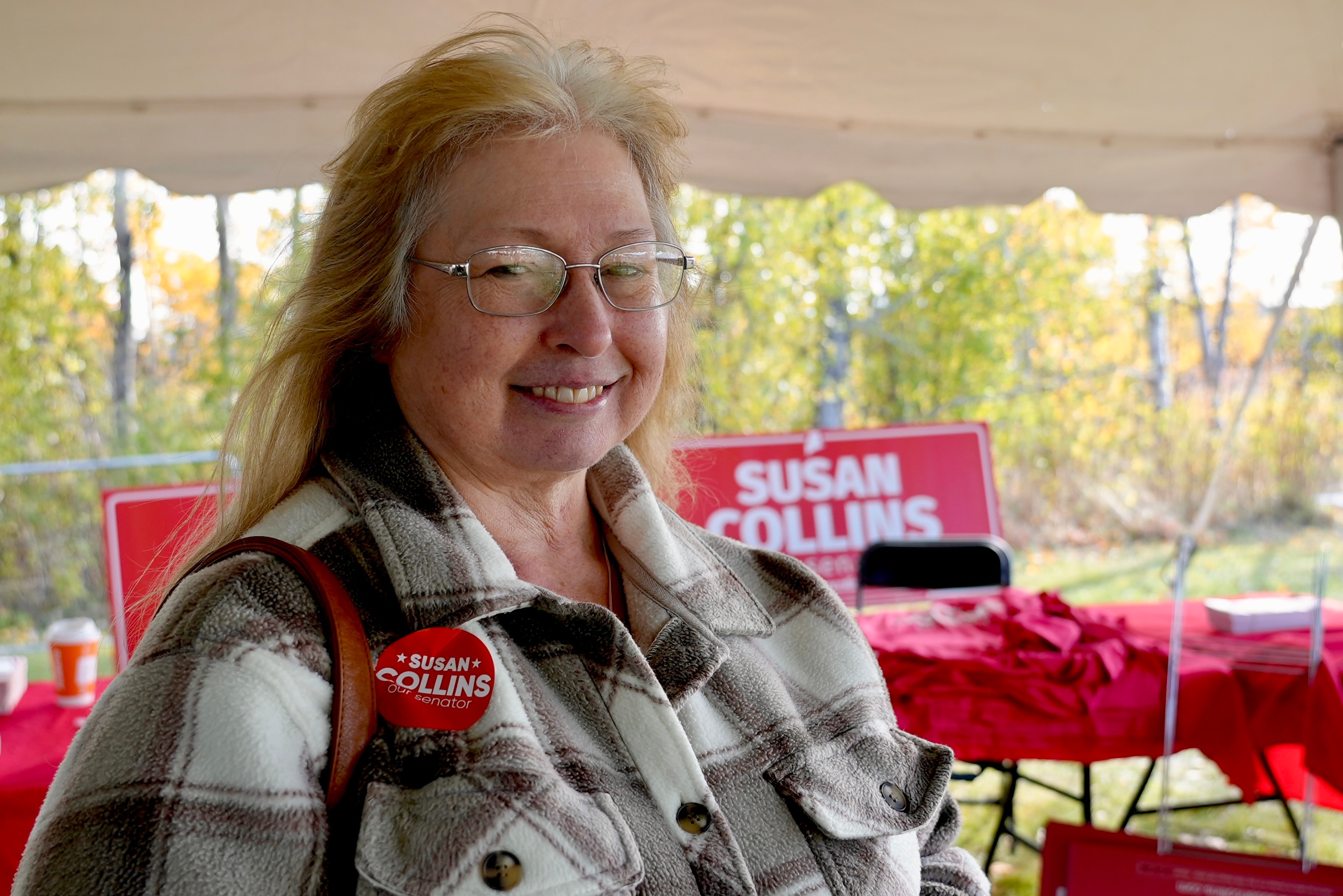 Lisa Thomas is pictured in front of a table displaying Susan Collins merchandise.