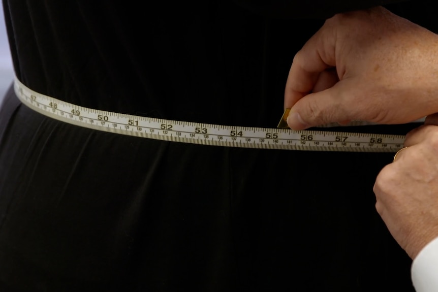 A doctor measures a woman's weight circumference.