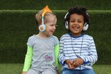 Two pre-school children wearing headphones and smiling.