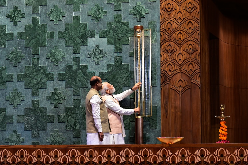 Two men placing a sceptre onto a wall. 