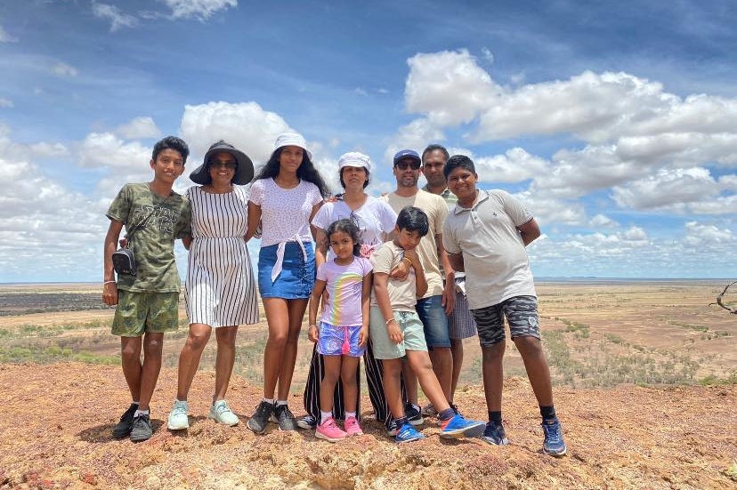A family of parents and children poses for a happy snap on the top of a hill in outback Queensland.