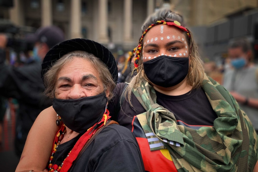 Aunty Shirley Blackwood and her daughter Tamara wearing black face masks and accessories in the colours of the Aboriginal flag.