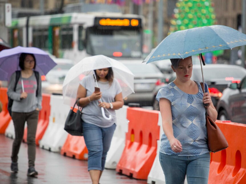 Pedestrians rush through the rain as storms hit Melbourne.
