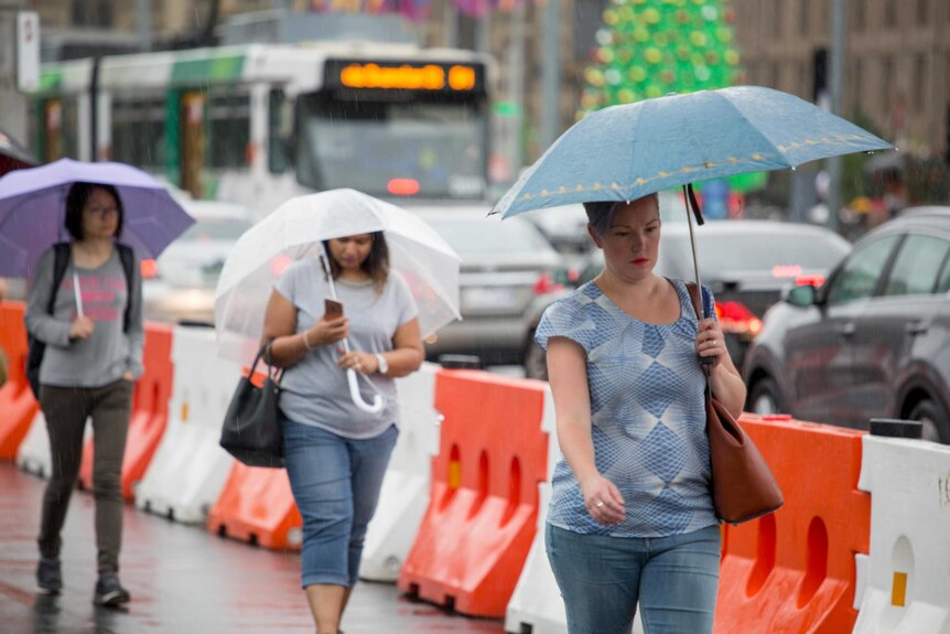 Pedestrians rush through the rain as storms hit Melbourne.