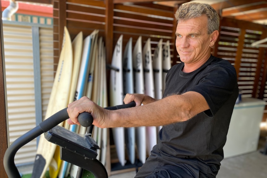 A man sits on his exercise bike in his garage