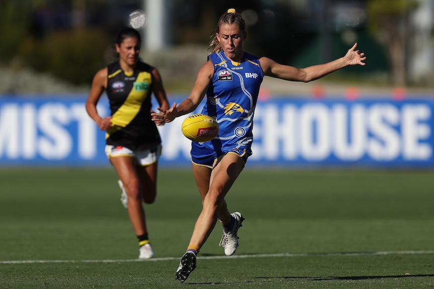 Aimee Schmidt goes to kick the ball while a defender runs up behind her.