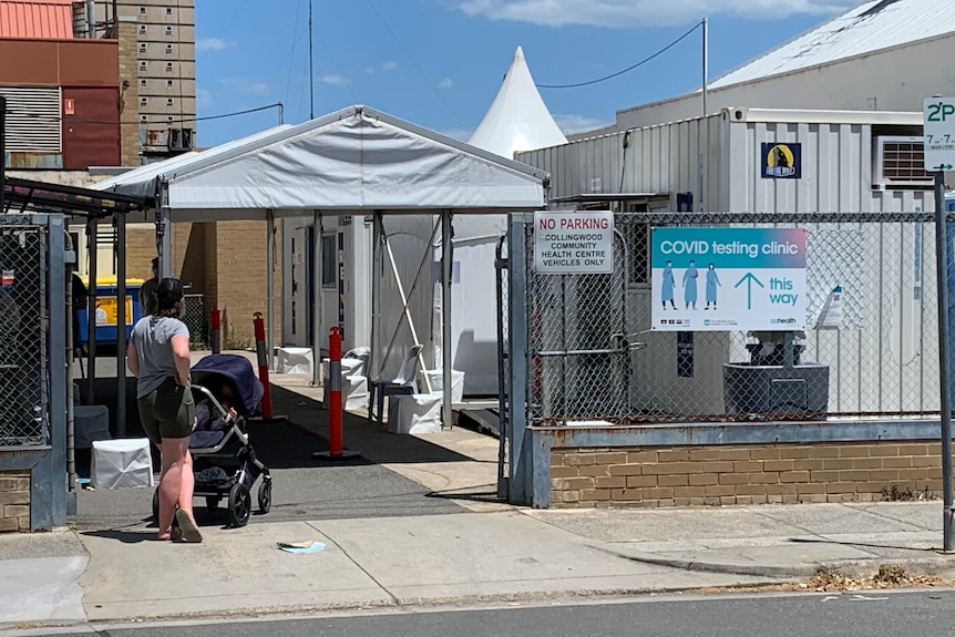 A sign directs people into a COVID-19 testing site, with a tent pitched above it.