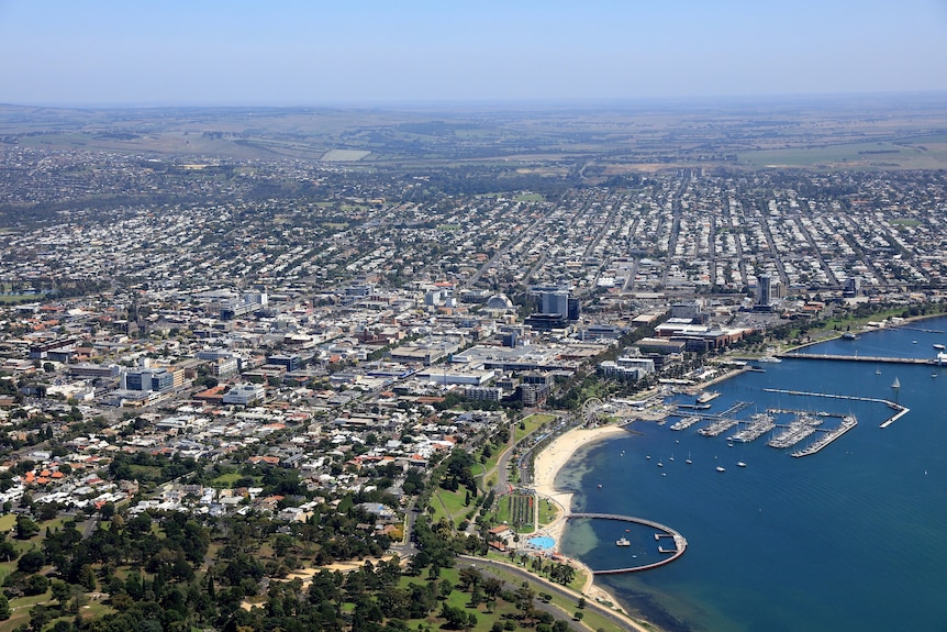 An aerial photo of Geelong showing the city and waterfront on a sunny blue sky day.