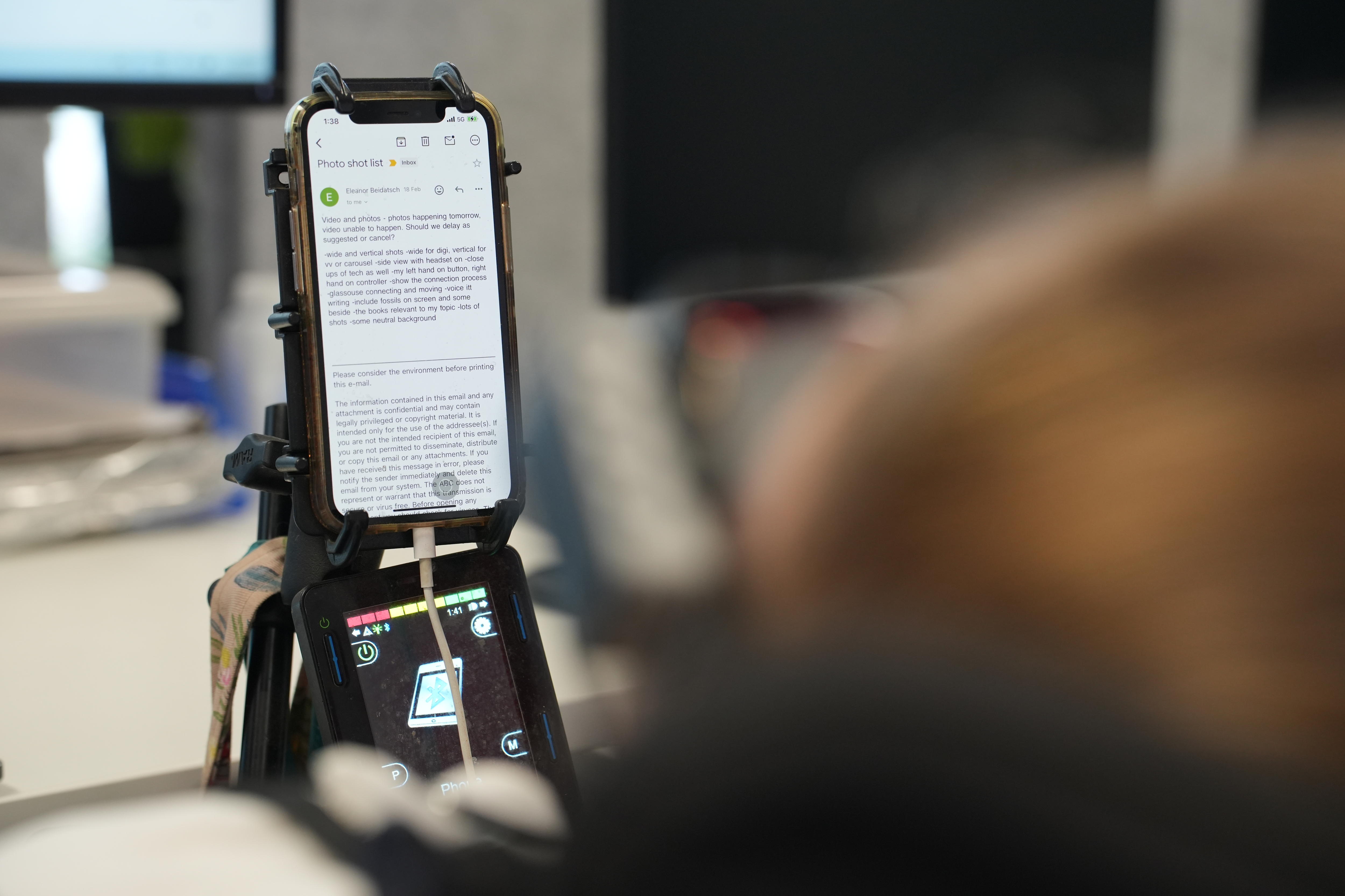 An iPhone mounted on a mobility wheelchair with an open Email.
