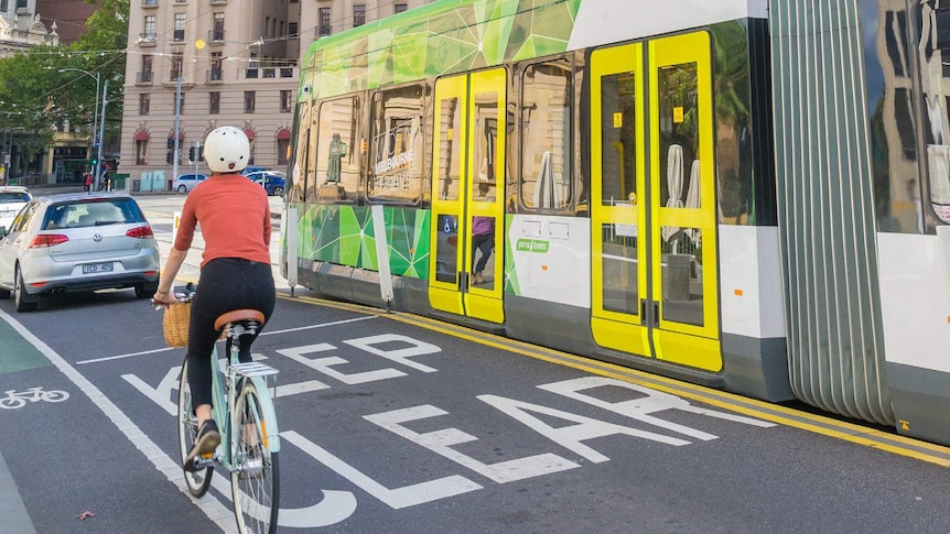 A bike in a city with a tram.