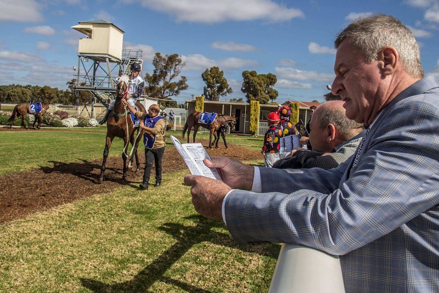 Punters line the fence of the marshalling yard at the Kalgoorlie Boulder Racing Club.