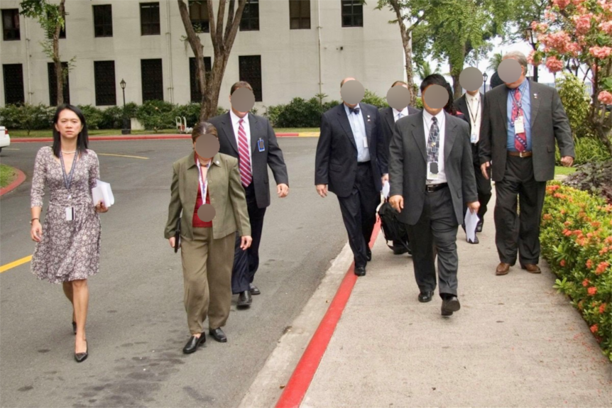 a GROUP OF GOVERNMENT OFFICIALS IN BUSINESS ATTIRE OUTSIDE A GOVERNMENT BUILDING