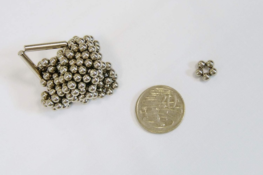 Five magnetic balls next to a 20 cent piece, from a large bundle that were part of a magnetic toy set bought online.