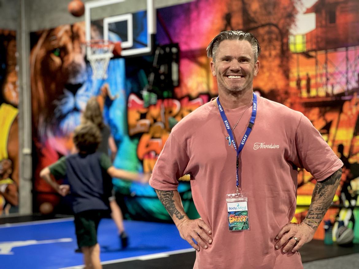 Man smiling at camera, basketball court behind