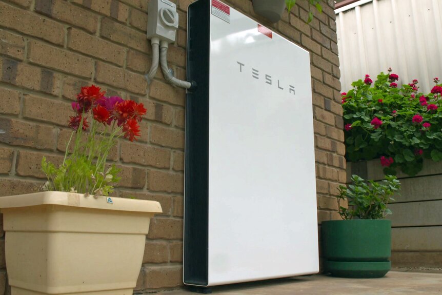 A Tesla battery attached to a brick wall.