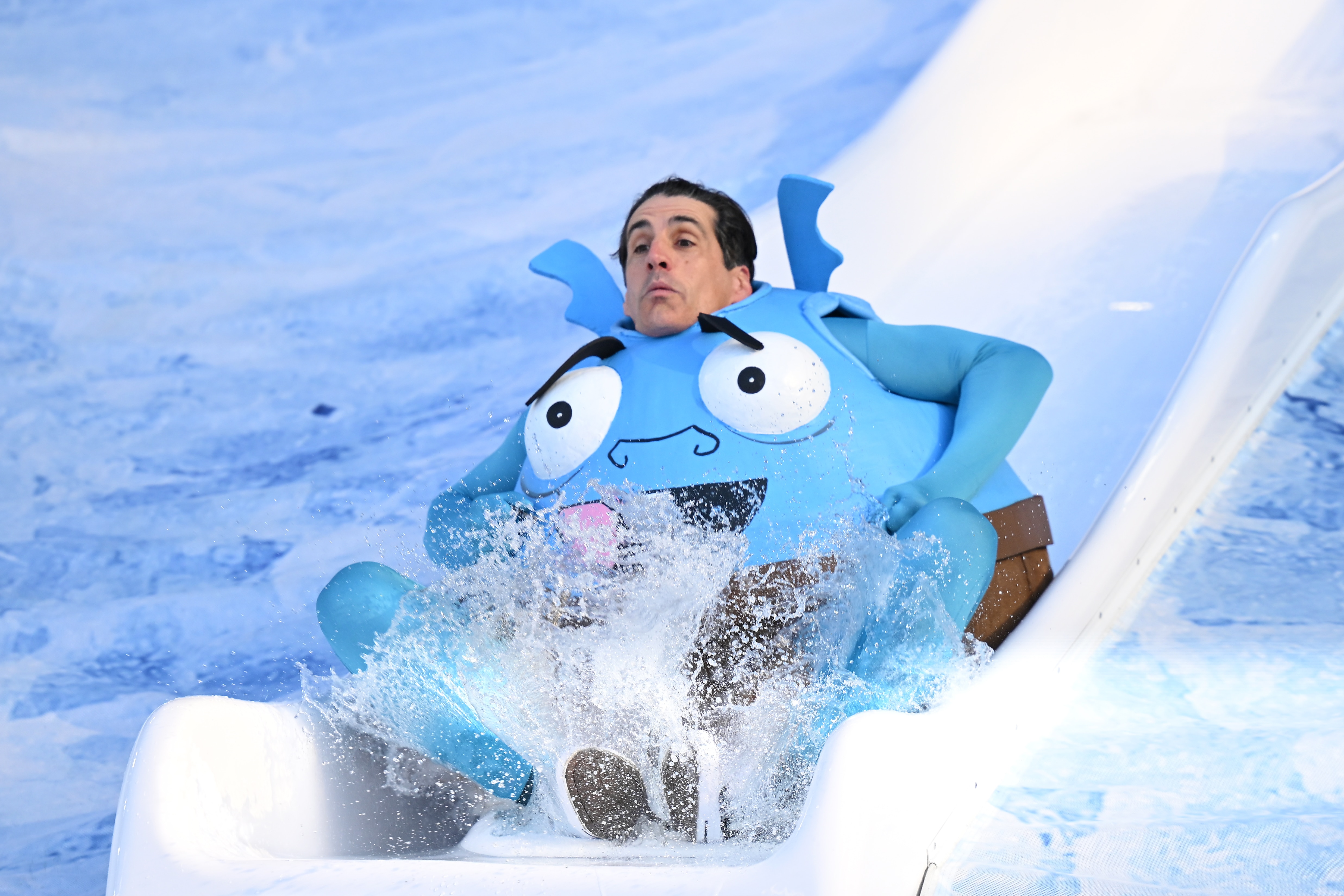 El comediante Andy Lee participa en Big Freeze, deslizándose por un tobogán hacia un charco de agua helada.