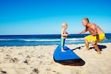 A father teaching a son to surf on land