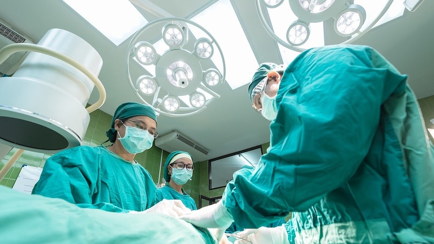 Three surgeons pictured in the operating room performing surgery