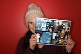 Young woman holding up comic book