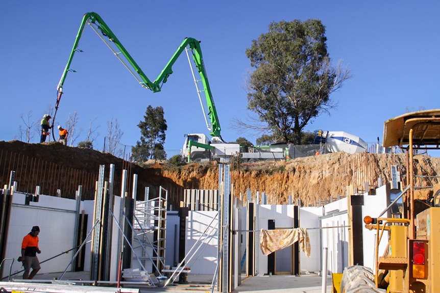 Workers pour concrete into the housing frame.