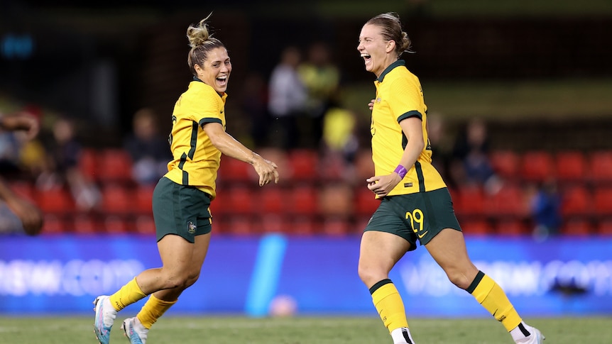 Two soccer players wearing yellow and green jump in the air during a game