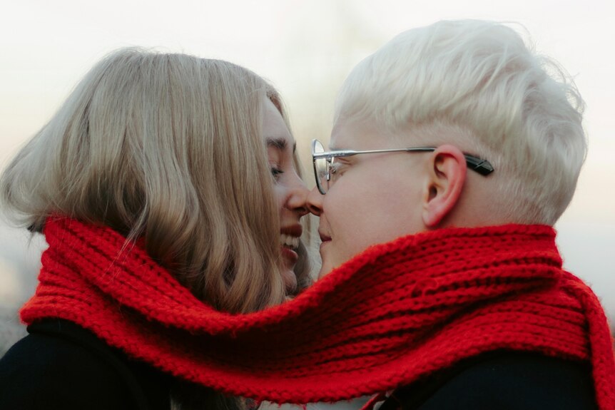 two women smiling close wearing a scarf