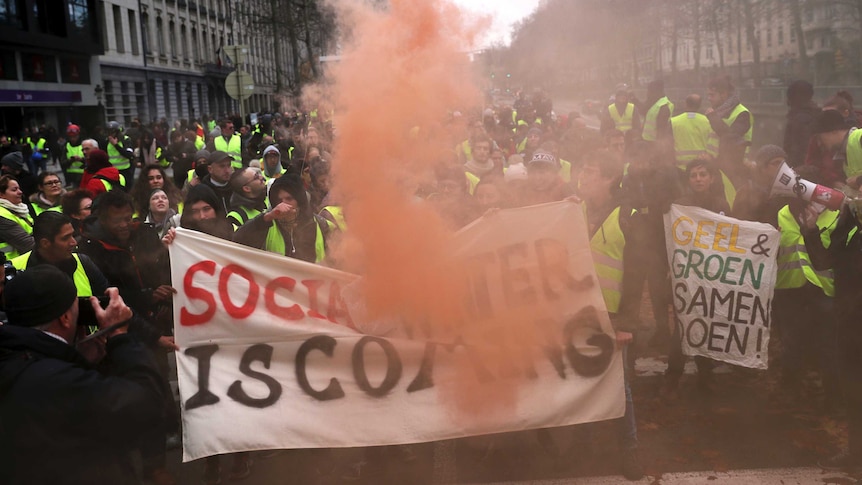 A large crowd of people in yellow vests gather around a sign that says "social winter is coming".