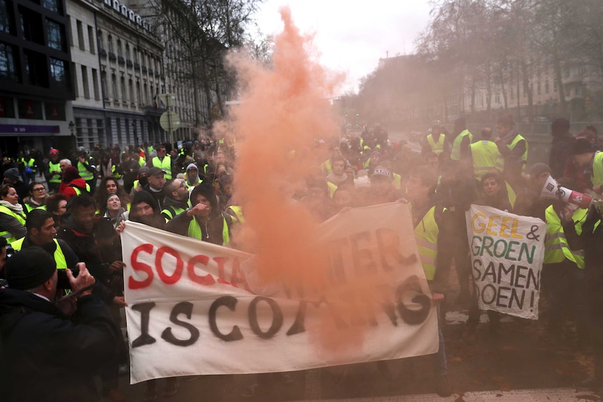 A large crowd of people in yellow vests gather around a sign that says "social winter is coming".