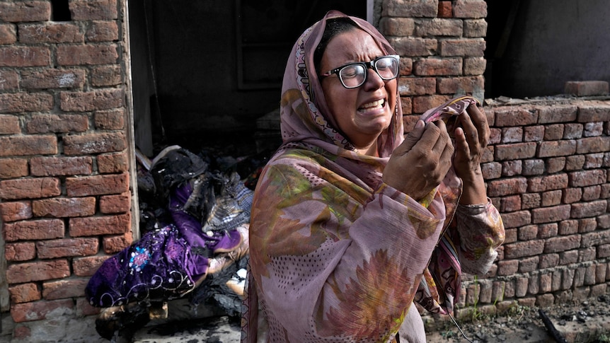 A Christian woman weeps after looking at her home vandalized by an angry Muslim mob.