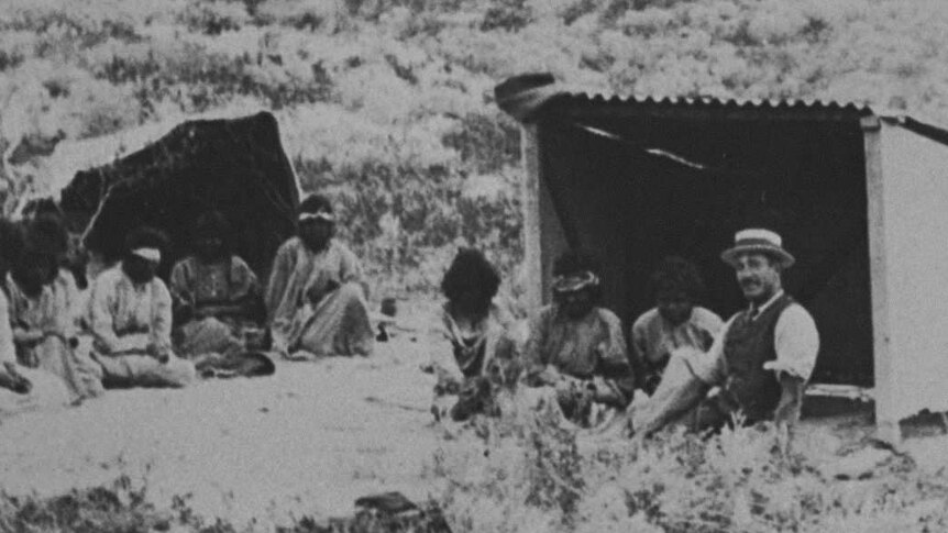 Historic photo of a group of people sitting outside huts of the lock hospital islands off WA's coast
