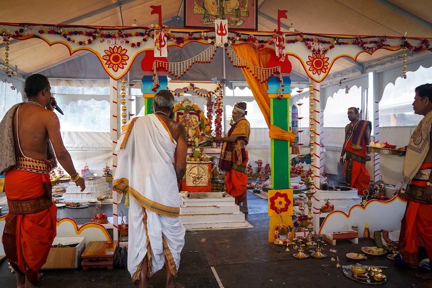 Several Hindu priests stand around a shrine during a ceremony