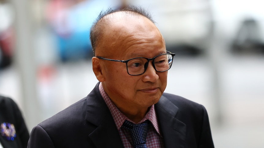 Di Sanh Duong wearing a suit and glasses.