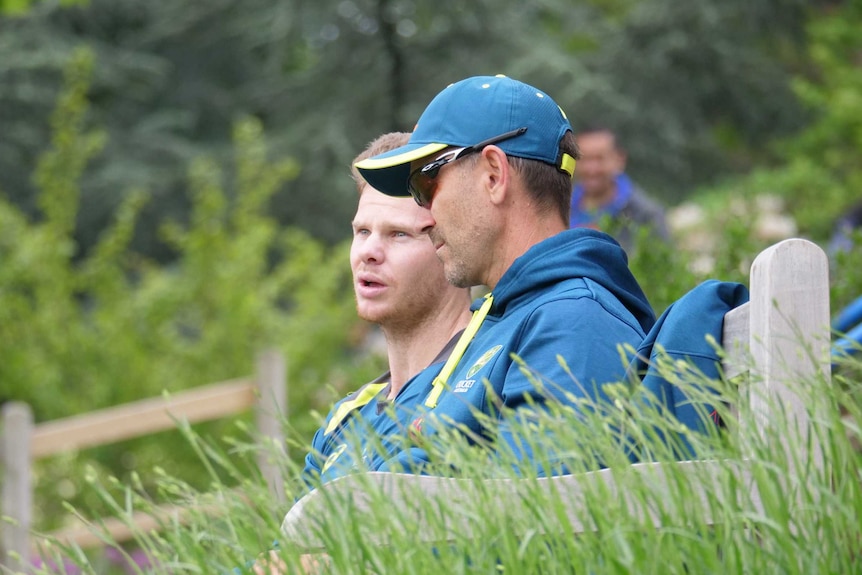 Justin Langer and Steve Smith sitting on a park bench having a private conversation.