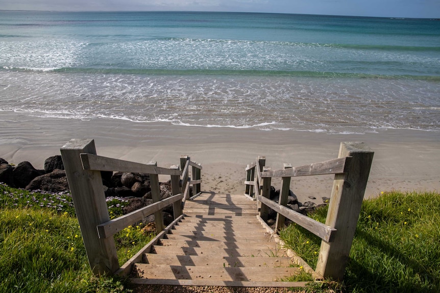 Wooden steps lead down to a beach.