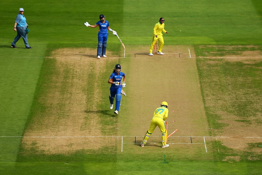 Two cricket teams, one in yellow, the other in blue, play a game