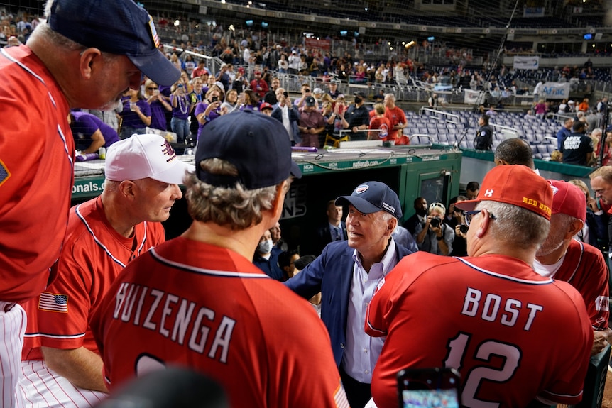 President Joe Biden visits the Republican dugout as he attends the Congressional baseball game