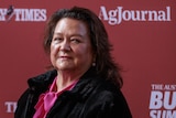 Gina Rinehart stands in front of advertising for an event media conference.