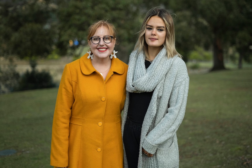 Two women standing in a park.