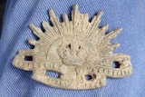 A very old war badge and a cross made out of spent ammunition.