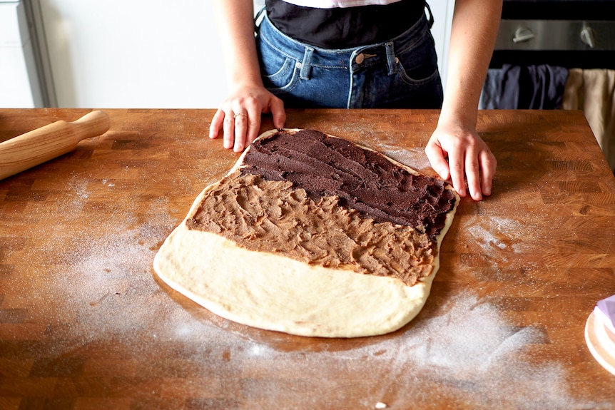 Dough for Swedish knots rolled out and filled with one-third chocolate paste, one-third cinnamon paste and the remainder plain.