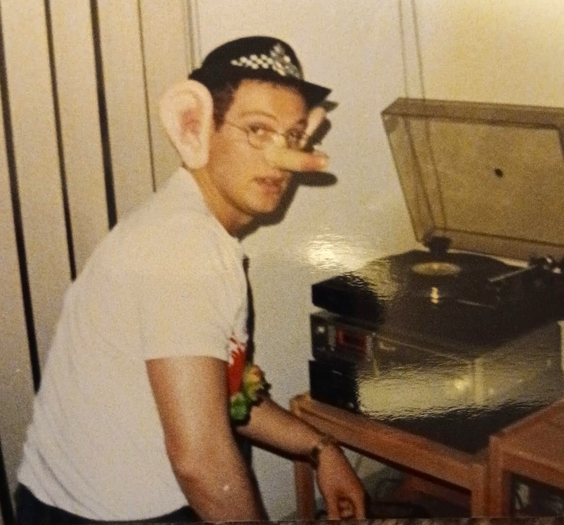 A man dressed in large ears and a Pinocchio nose with a police hat. 
