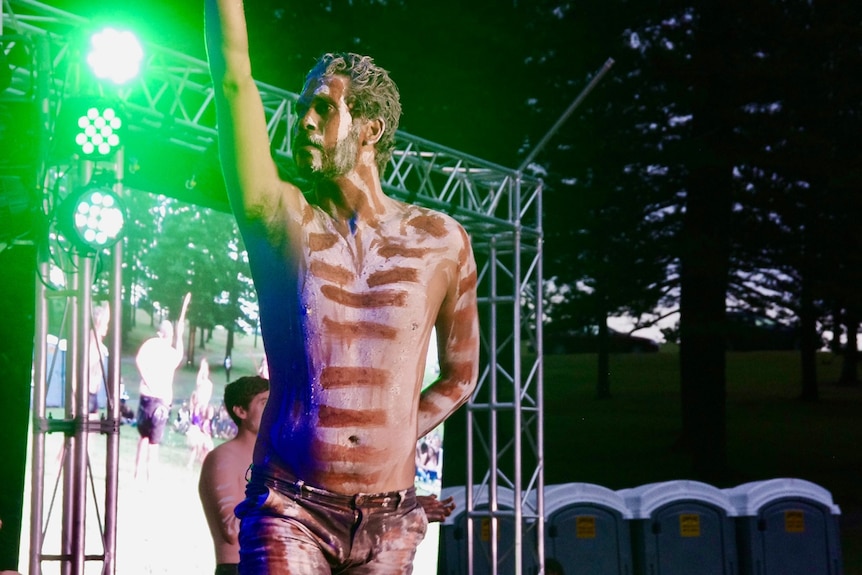 A mid shot of an Indigenous man performing on stage