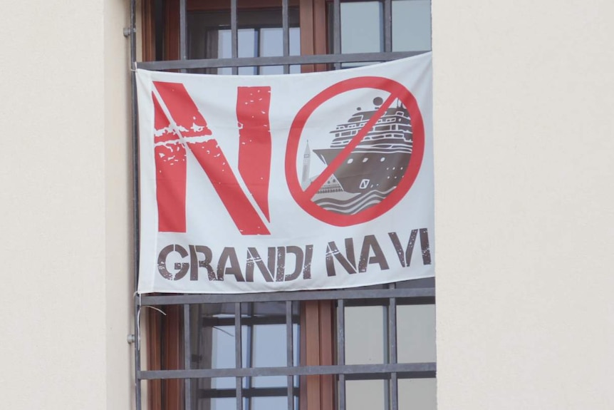 A sign with the words No Grandi Navi in a window.