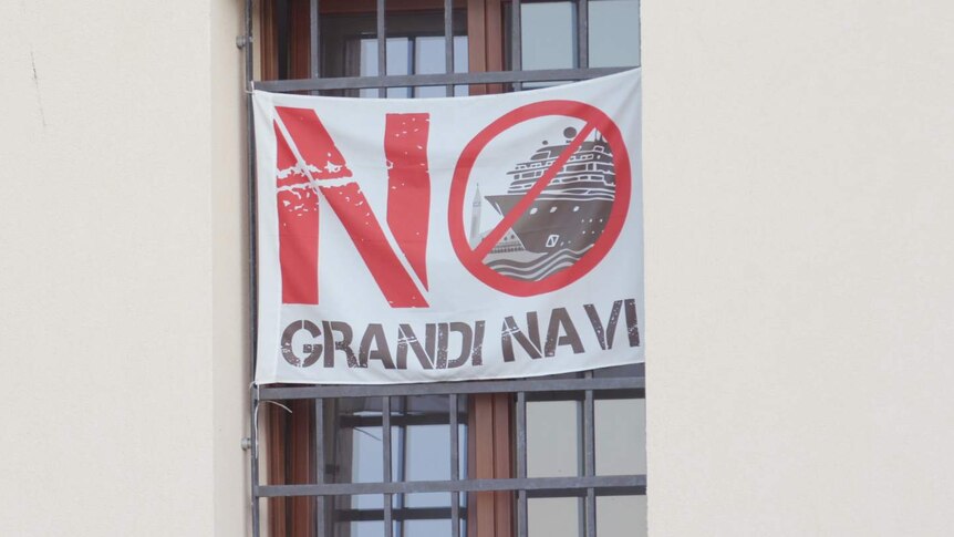A sign with the words No Grandi Navi in a window.
