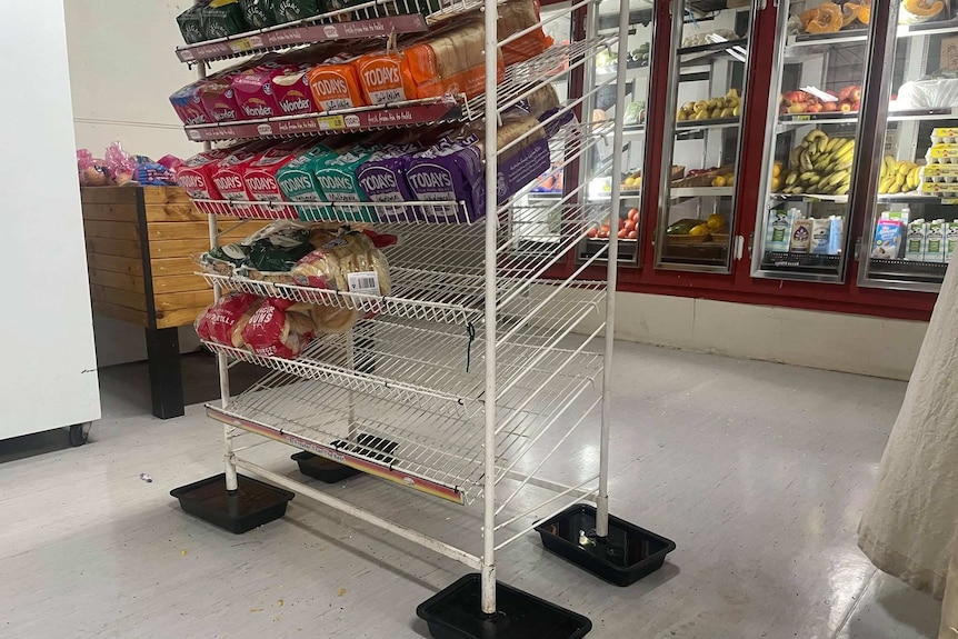 A shelf rack of loaves of bread on display has each leg in a bucket of water.