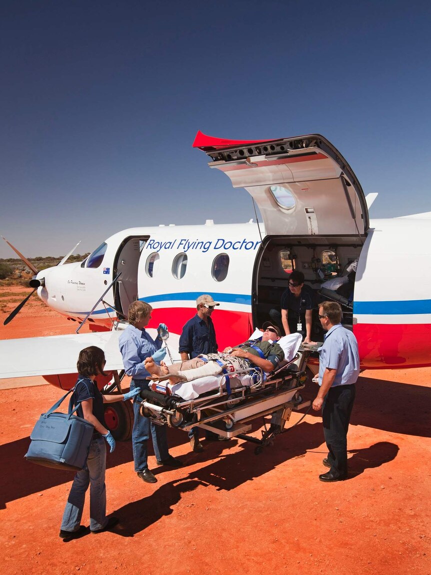 Mano n stretcher in desert being loaded onto small aircraft